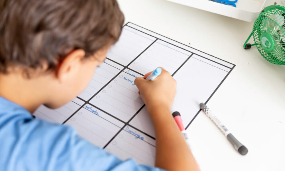 bambino che scrive su un calendario e impara l'organizzazione del tempo