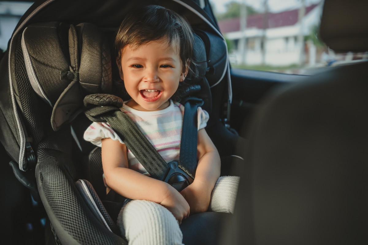 Bambina sorridente seduta nel seggiolino auto