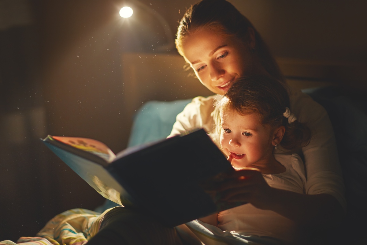 Mamma e figlia nel letto con libro