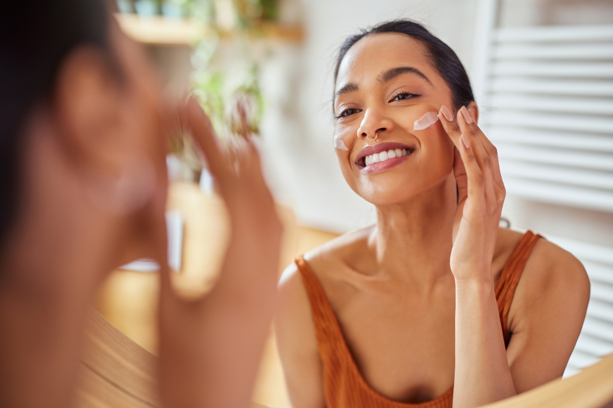 Ragazza si prende cura della pelle applicando crema allo specchio