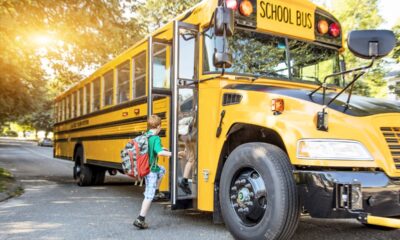 Bambino sale sullo scuolabus giallo tipico degli USA per la scuola