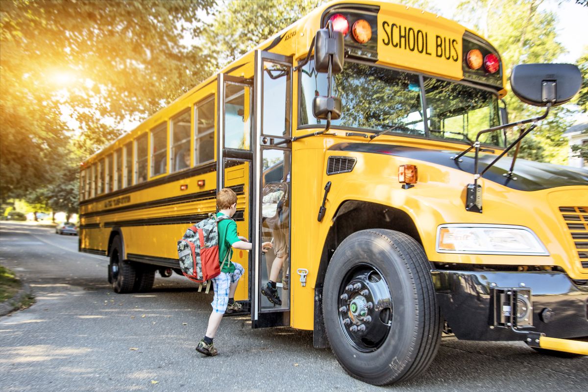 Bambino sale sullo scuolabus giallo tipico degli USA per la scuola